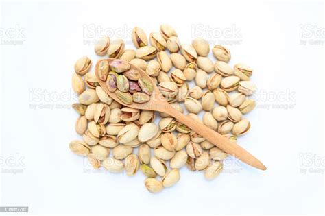 Pistachio Nuts Isolated On White Background With Wooden Spoon Top View