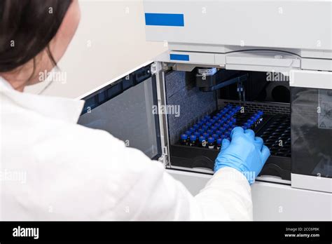 Scientist In A White Lab Coat Putting Vial With A Sample Into