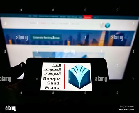 Person holding cellphone with logo of Saudi Arabian bank Banque Saudi Fransi (BSF) on screen in ...