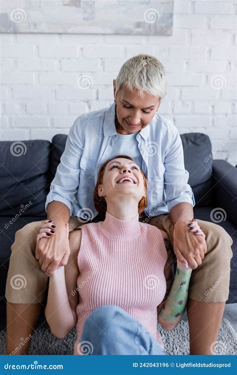 Cheerful Lesbian Couple Holding Hands And Stock Photo Image Of Sofa