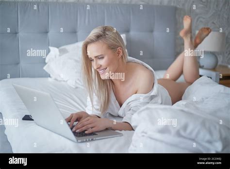 A Smiling Blonde Woman Lying Down The Bed In Front Of Her Laptop Stock Photo Alamy