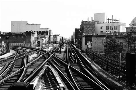 Black And White Photograph Of Train Tracks In An Urban Area With