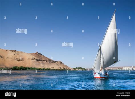 A Traditional Nile Felucca Sails Past Ancient Egyptian Ruins On Top Of