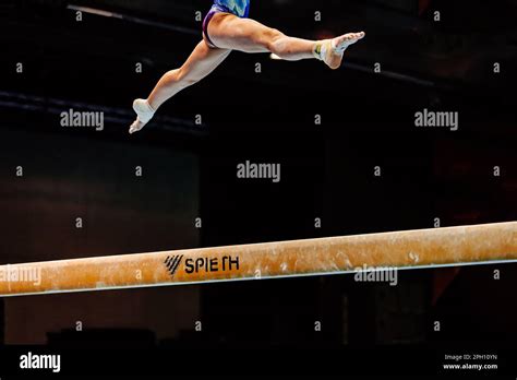Female Gymnast Exercise Split Jump In Balance Beam On Black Background