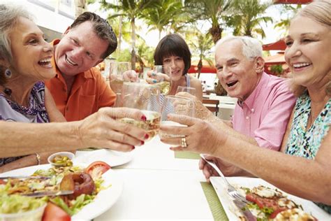 Grupo De Amigos Mayores Que Disfrutan De La Comida En Restaurante Al