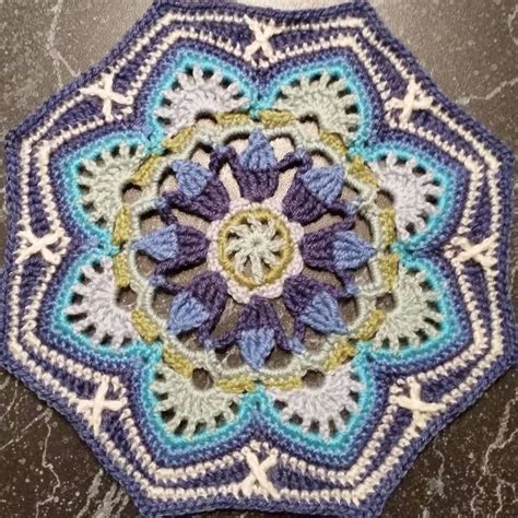 A Crocheted Doily Is Sitting On A Table With The Center Piece In Blue