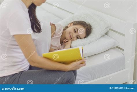 Loving Mother Reading Bedtime Story To Her Daughter In Bed Cute Girl