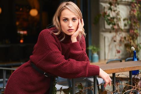 Belle fille blonde en pull tricoté regardant en toute confiance à huis clos en plein air Photo