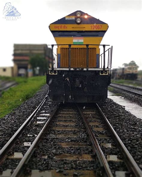 A Yellow And Black Train Traveling Down Train Tracks