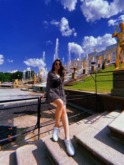 A Woman Sitting On Some Steps In Front Of A Fountain