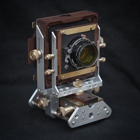 An Old Fashioned Camera Sitting On Top Of A Wooden Stand With Metal