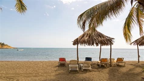 Premium Photo Deck Chairs And Thatched Roof Umbrella At Beach