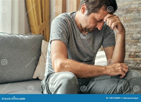 Depressed Sulking Man Sitting Alone At Living Room Sofa And Thinking