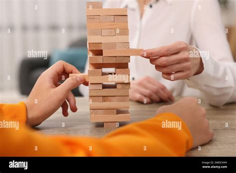 People Playing Jenga Tower At Wooden Table Indoors Closeup Stock Photo