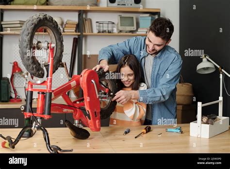 Happy Young Man And His Daughter Using Wrench To Fix Part Of Bicycle