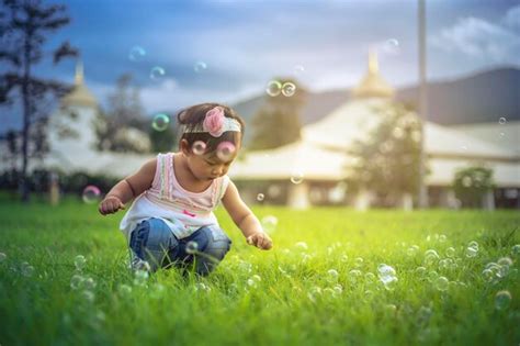 Premium Photo Girl Crouching On Grass Against Sky