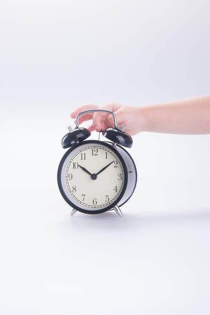 Premium Photo Cropped Hand Holding Alarm Clock Against White Background