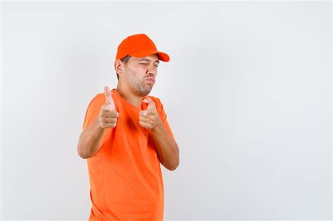 Free Photo Delivery Man In Orange T Shirt And Cap Imitating Gun Gesture