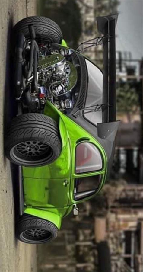 A Green Car Hanging Off The Side Of A Building With Its Wheels In The Air