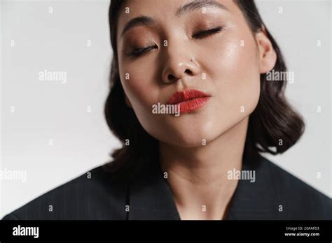 Brunette Asian Woman Wearing Jacket Posing On Camera Isolated Over White Background Stock Photo