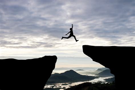 Man Jump Through The Gap Between Hillman Jumping Over Cliff On Sunset