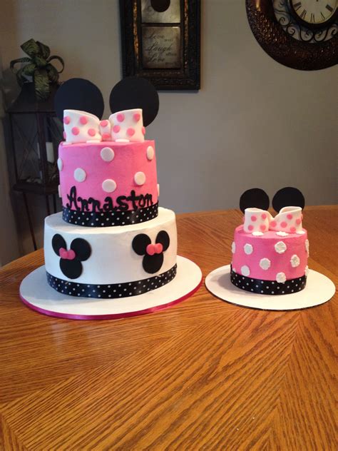 Two Minnie Mouse Cakes Sitting On Top Of A Wooden Table