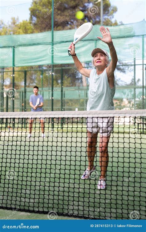 Sporty Mature Woman Padel Player Hitting Ball With A Racket On Hard