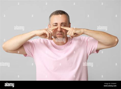 Ill Mature Man Pointing At Nose On Grey Background Stock Photo Alamy