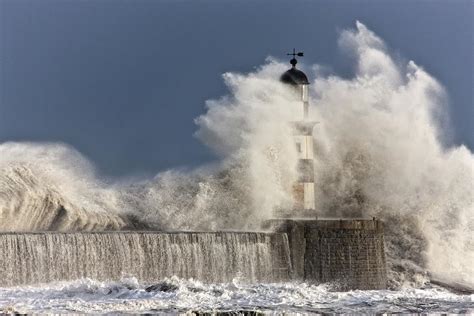 Waves Crashing Up Against A Lighthouse Photograph by John Short