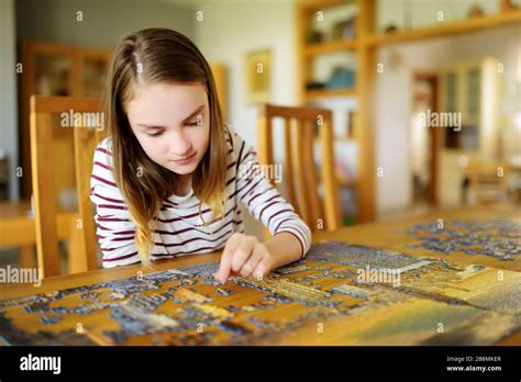 Cute young girl playing puzzles at home. Child connecting jigsaw puzzle ...