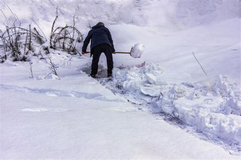 A Man Cleans Snow After A Blizzard On A Sunny Winter Morning Stock