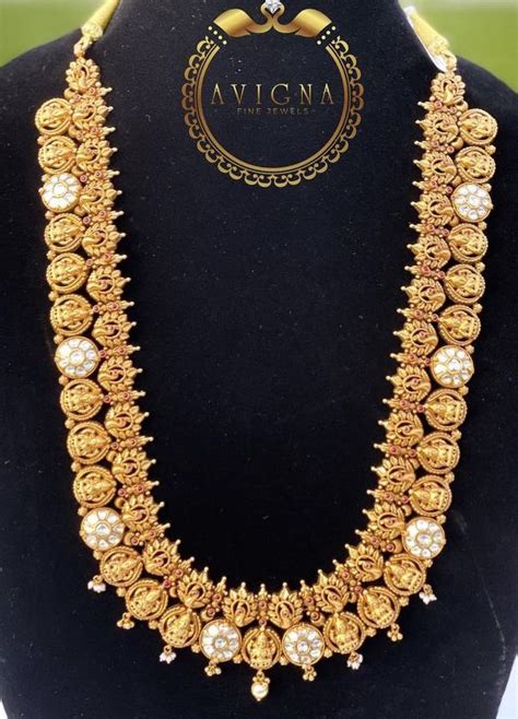 A Gold Necklace With Pearls On Display In A Black Stand And The Words