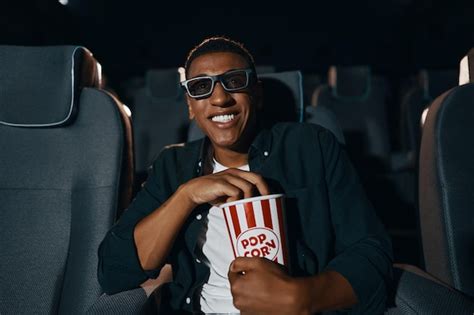 Homem afro americano em óculos 3d comendo pipoca e assistindo filme no