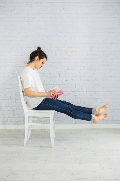 Femme Aux Pieds Nus Appréciant La Lecture Sur La Chaise Photo Gratuite