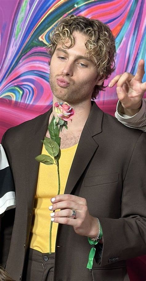 A Man In A Suit Holding A Rose And Pointing To The Side With His Finger