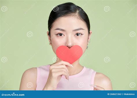 Playful Asian Woman Holding Paper Heart In Front Of Her Mouth Stock
