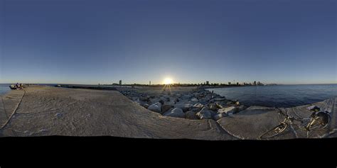 The Sun Is Setting Over Some Rocks By The Water And People Are Riding