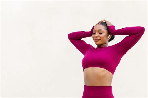 Mujer Negra Joven Alegre Que Ejercita En El Fondo Blanco Usando Earpods