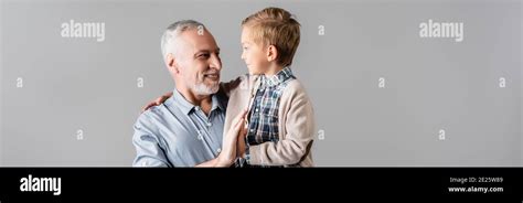 Happy Man Giving High Five To Grandson While Holding Him Isolated On