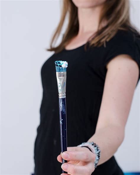 A Woman Holding A Blue And White Toothbrush In Her Right Hand While