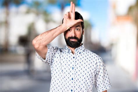 Hombre guapo morena con barba haciendo señal estúpida Foto Premium