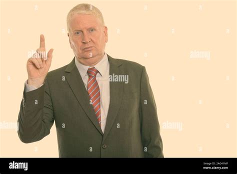 Studio Shot Of Mature Businessman Pointing Finger Up Stock Photo Alamy