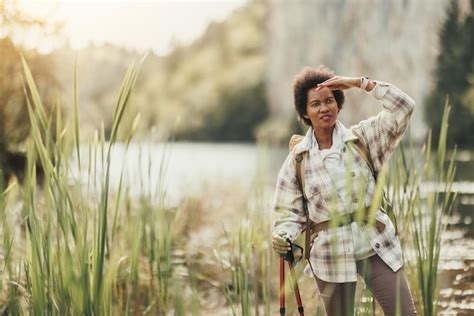 Premium Photo Mature Black Woman With Backpack Standing By The Lake