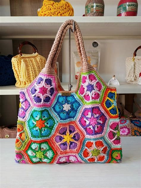 Two Crocheted Purses Sitting On Top Of A White Shelf Next To Each Other