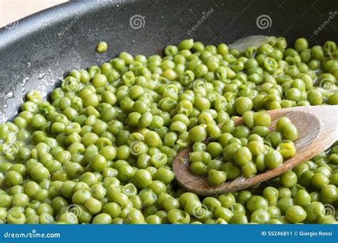 Cooking Green Peas In Black Frying Pan With Wooden Spoon Stock Image