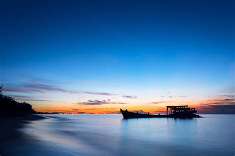 An Image Of A Wrecked Fishing Boat By The Sea At Sunset Stock