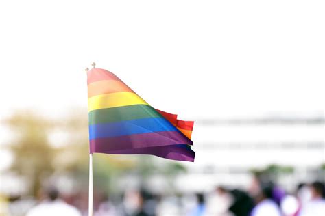 Pride Rainbow Lgbt Gay Flag Holding In Hand And Being Waved In The Breeze Against Blue Sky