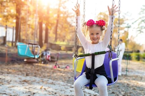 Premium Photo Portrait Of Smiling Girl On Swing In Playground