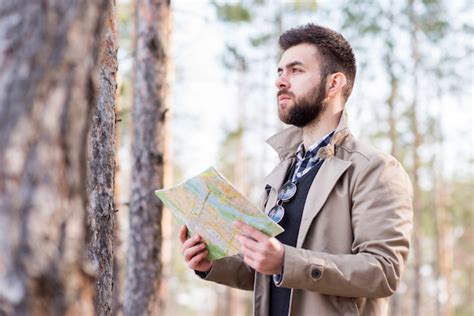 Jovem alpinista masculina em pé na floresta segurando o mapa na mão