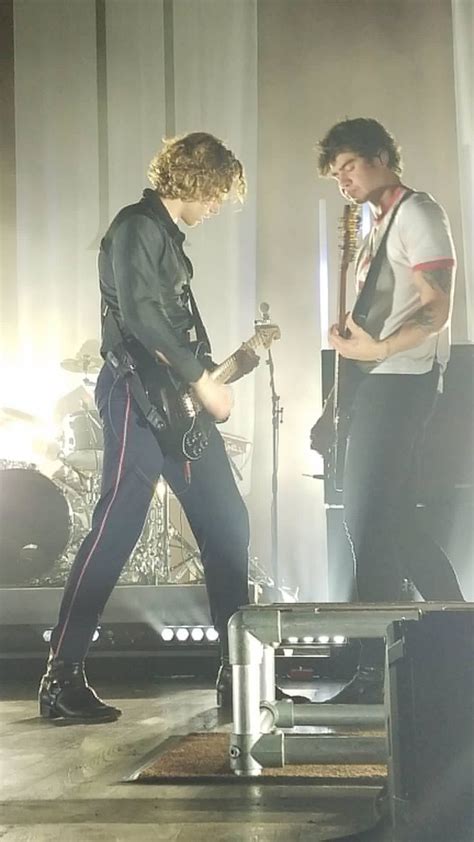 Two People Standing On Stage With Guitars And Microphones